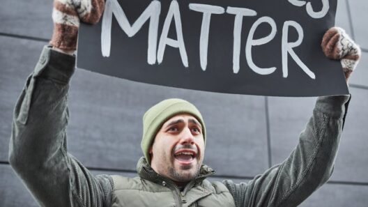 A man protests with a sign outdoors in winter attire, expressing a powerful message.
