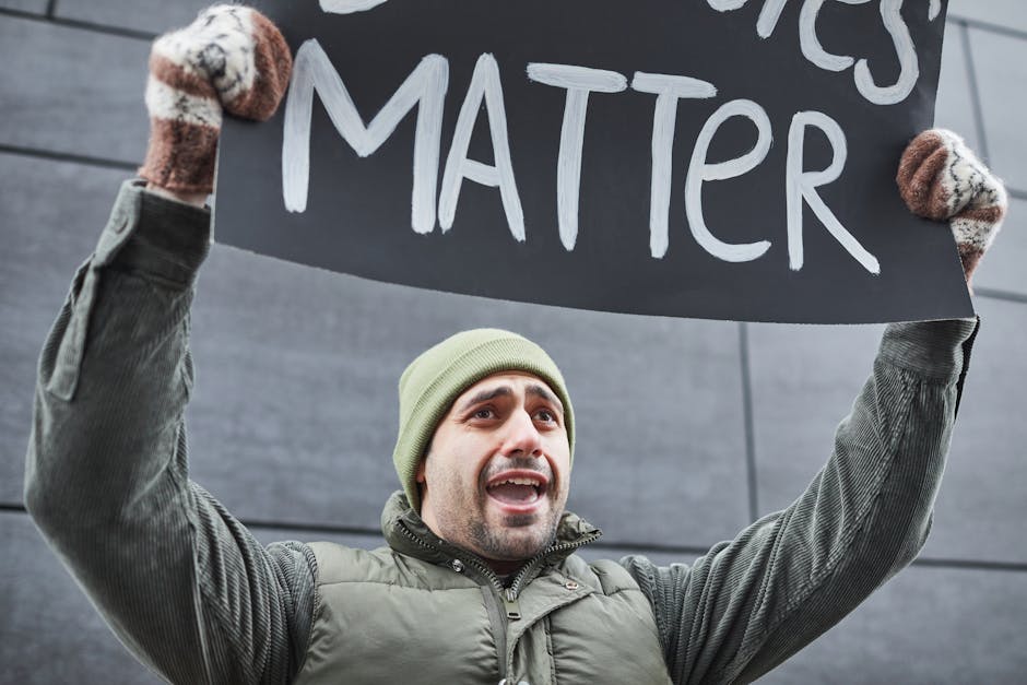 A man protests with a sign outdoors in winter attire, expressing a powerful message.