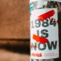 Street poster with '1984 is Now' theme highlighting surveillance in urban setting.