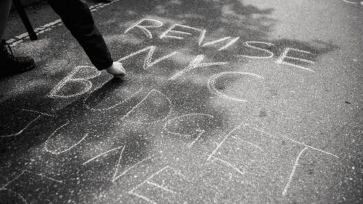 Person writing protest message with chalk on streets of NYC, urging budget revision.
