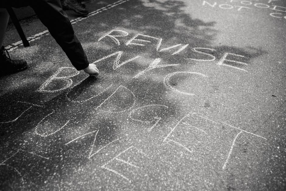 Person writing protest message with chalk on streets of NYC, urging budget revision.