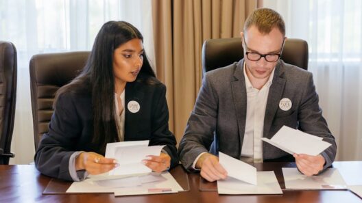 Two professionals in a meeting reviewing documents at a conference table.