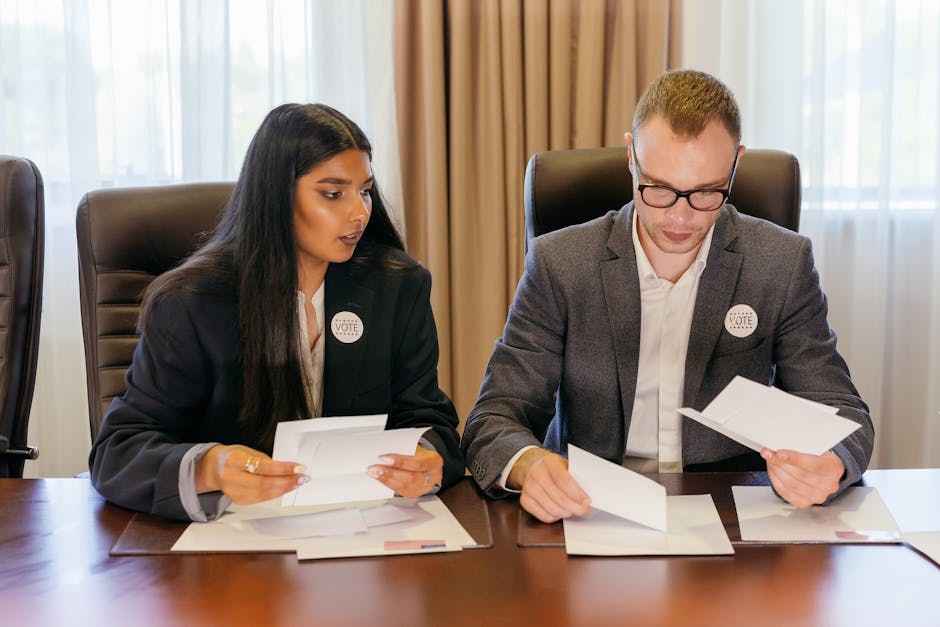Two professionals in a meeting reviewing documents at a conference table.