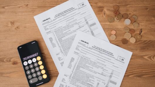 Top view of tax documents, calculator, and coins on wooden table.