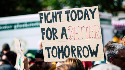Crowd holding a protest sign with 'Fight Today for a Better Tomorrow', outdoors and during the day.