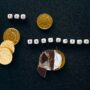 Creative concept of tax deductions using chocolate coins and letter tiles on a black background.