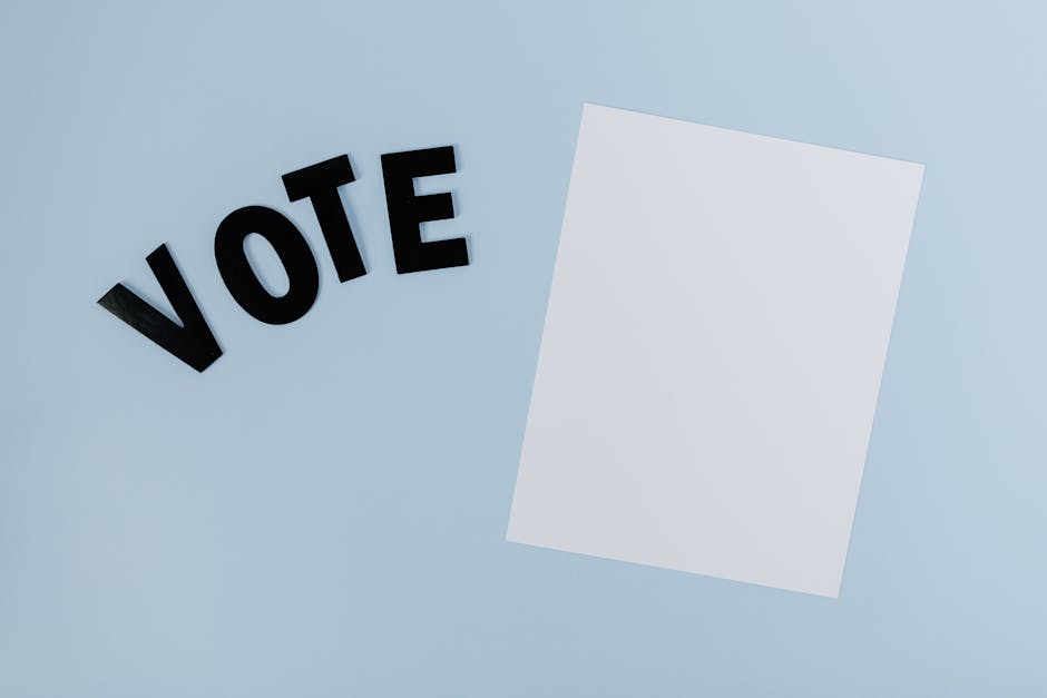 Flat lay of blank paper with 'VOTE' letters on light blue background, ideal for election-themed content.